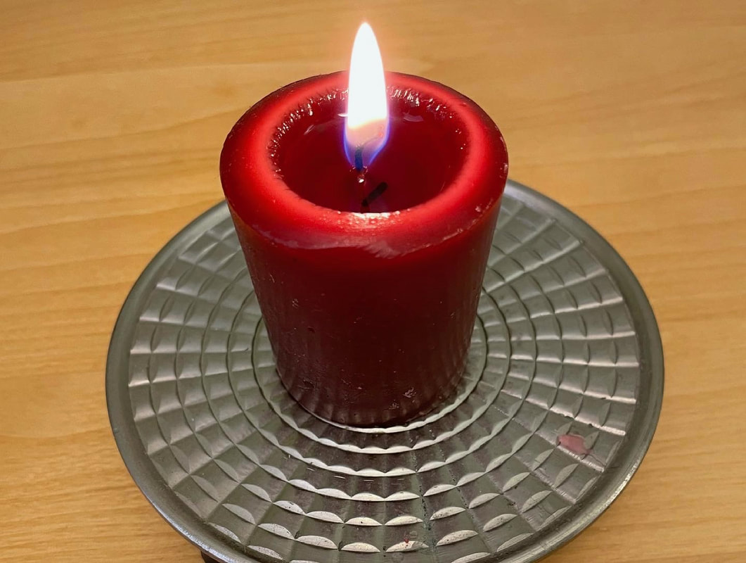 Lit red votive candle on round silver stand