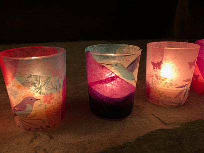 Three illuminated votive candle holders decorated with tissue paper for stained glass effect